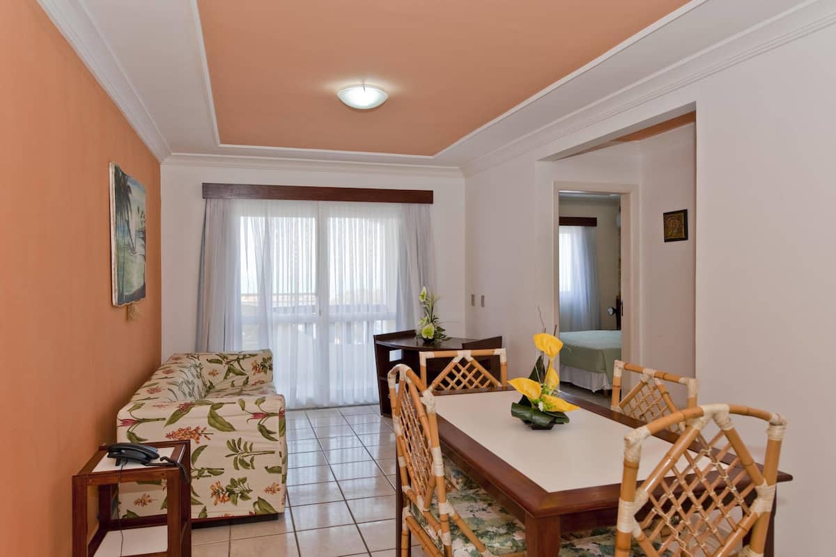 A living room with a sofa, dining table, chairs, and a small side table.