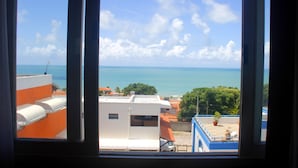 Blick durch ein Fenster auf ein Gebäude mit Blick auf eine Küstenlandschaft, bewölkter Himmel und ruhiges Meer.