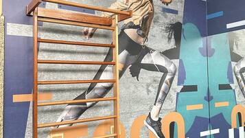 A gym with a wooden pull-up bar and a mirrored wall with a large 'GUTS' logo.