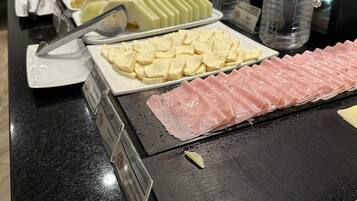 Un buffet con diverse pietanze, tra cui salumi, formaggi e altri piatti.