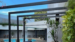A poolside area with wicker furniture, a round table, and potted plants. - Hotel Saint Paul (São José do Rio Preto)