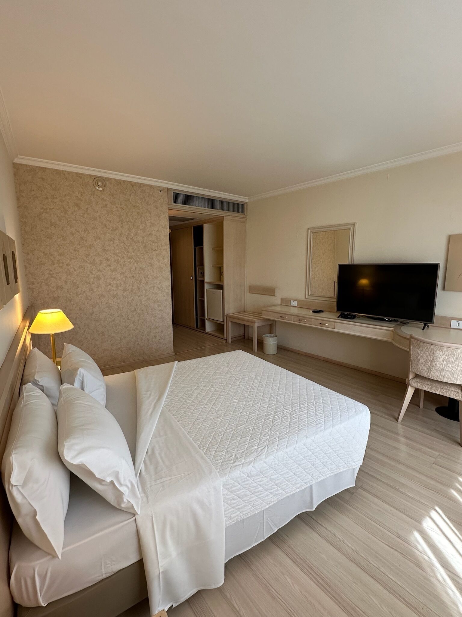 Una habitación de hotel con cama, escritorio, televisor y armario.