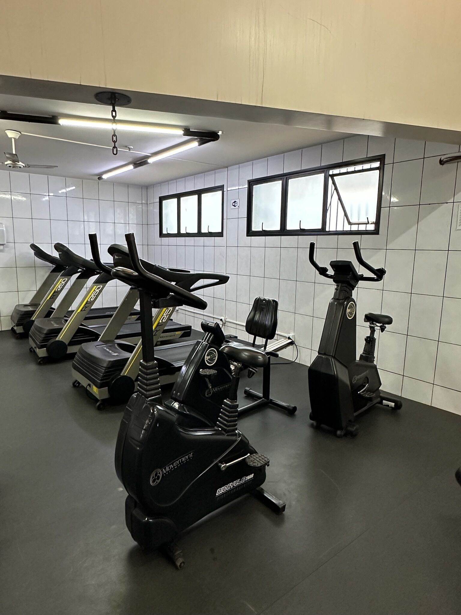 Une salle de sport équipée de vélos d’appartement, de tapis de course et d’un appareil d’aviron.