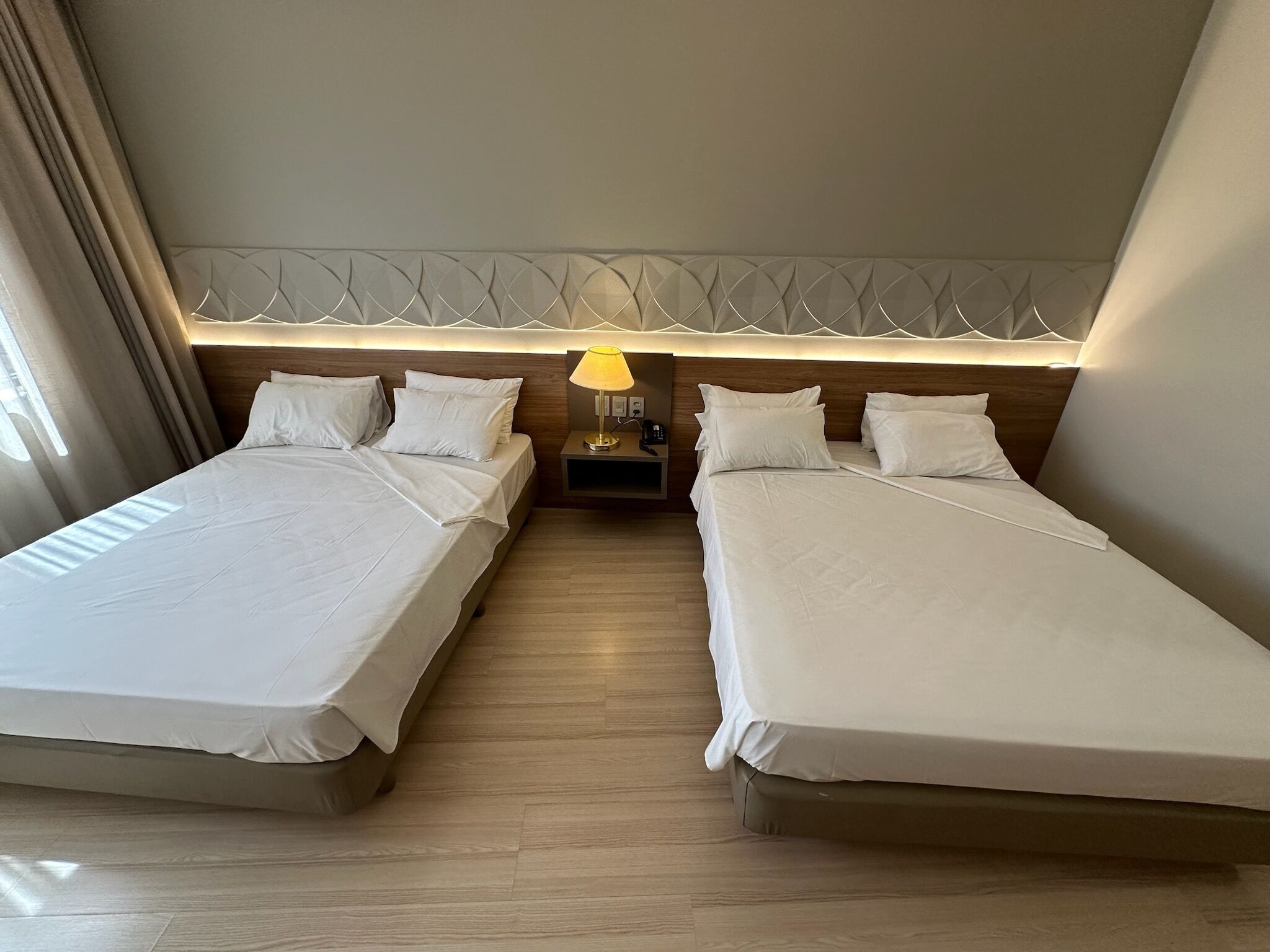Une chambre d’hôtel avec deux lits, une table de chevet avec une lampe et une tête de lit décorative.