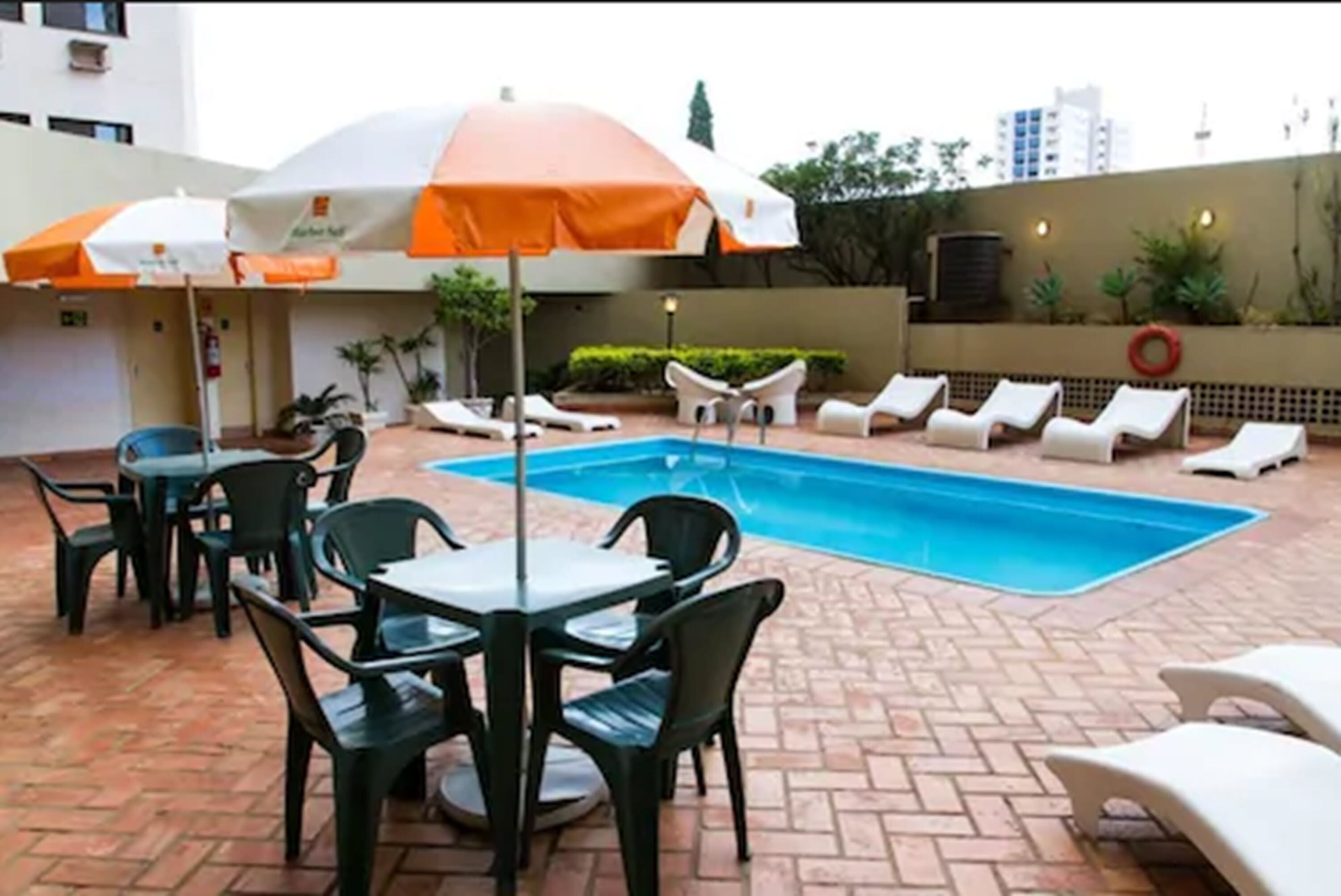 Ein Pool mit Liegestühlen und einem Tisch mit Stühlen in einem Innenhof.