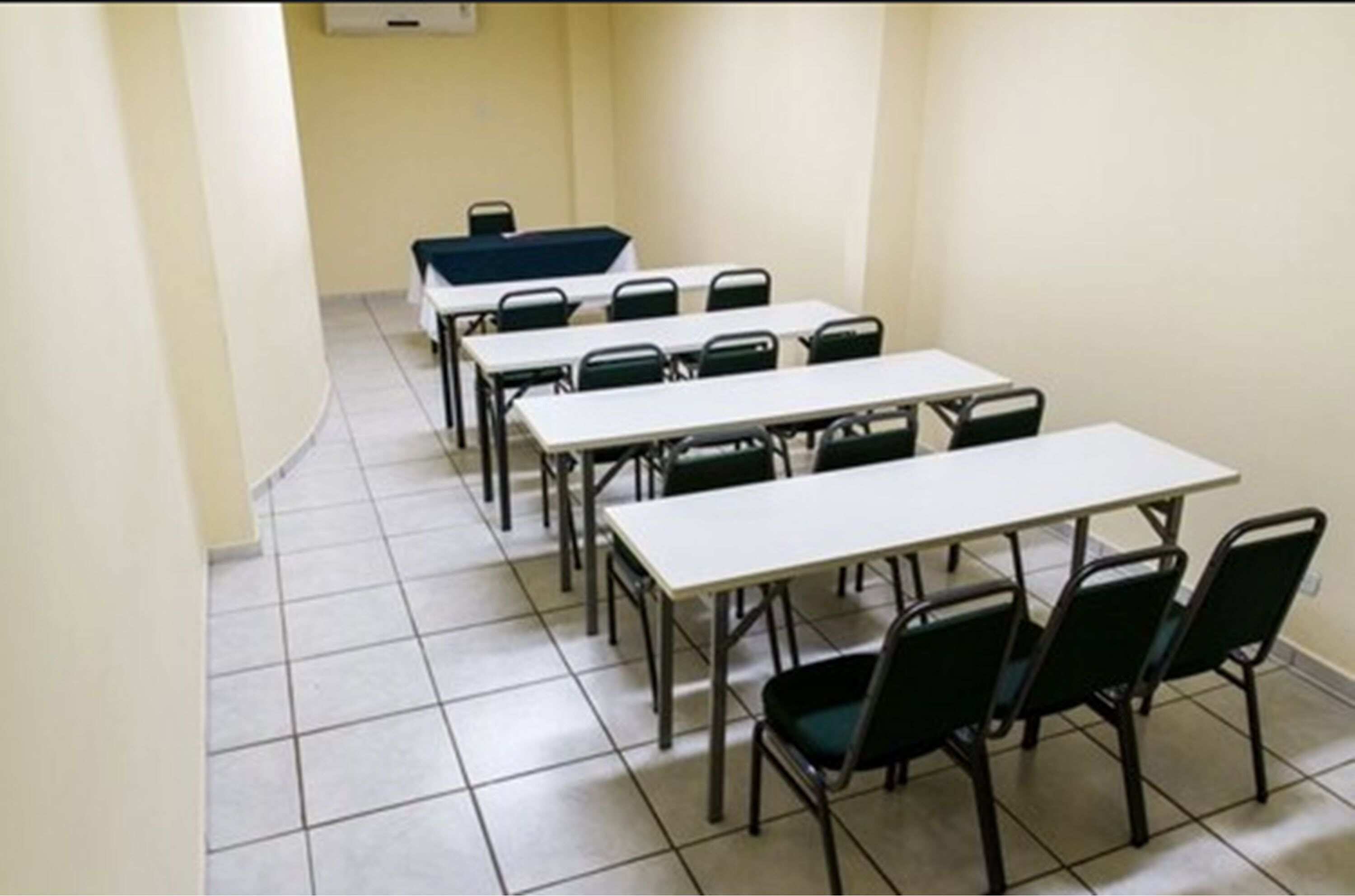 A conference room with multiple tables and chairs, a tiled floor, and a whiteboard on the wall.