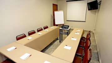 Een vergaderzaal met een lange tafel, stoelen, een beamer en een whiteboard.