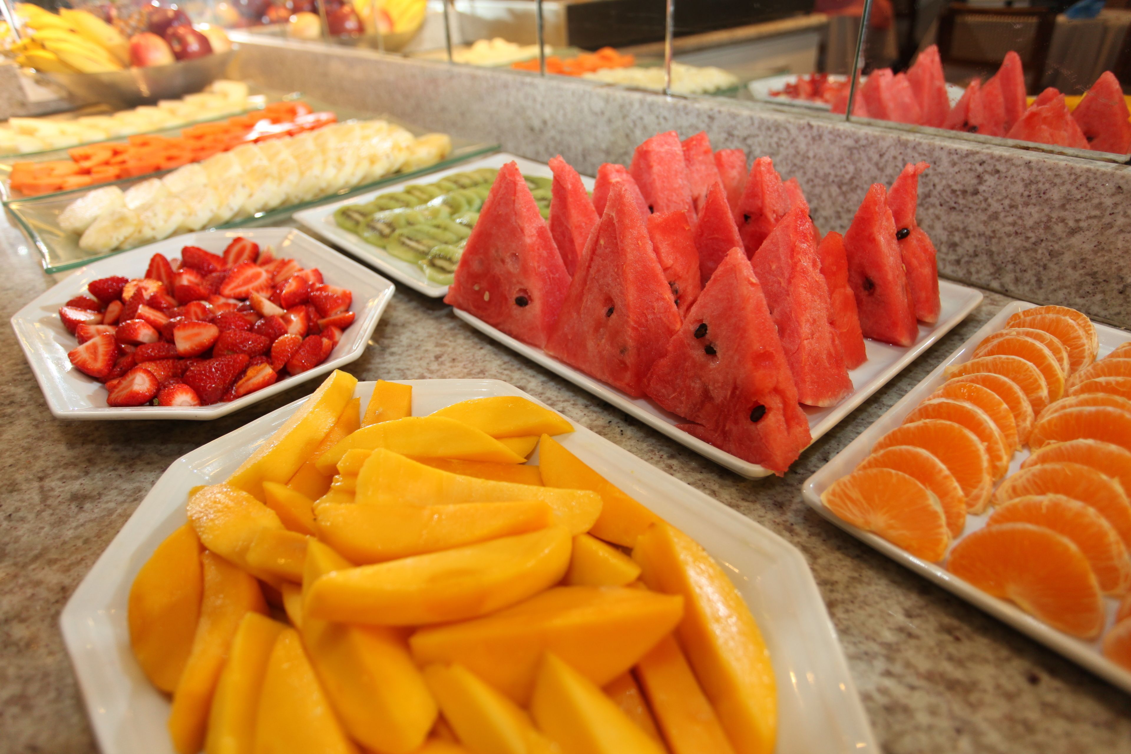 Buffet com diversas frutas, incluindo melancia, morangos, mangas e laranjas.