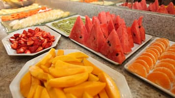 Buffet com diversas frutas, incluindo melancia, morangos, mangas e laranjas.