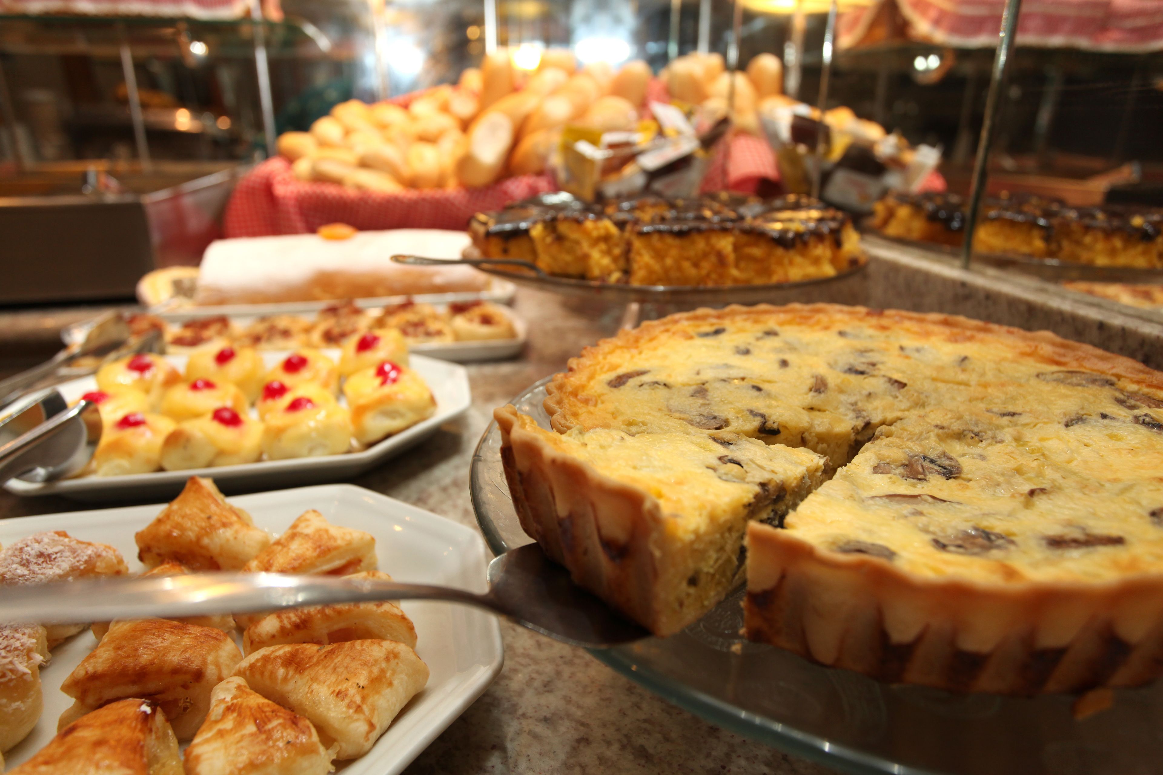 Variedad de productos horneados expuestos en un mostrador de vidrio, como tartas y pasteles.