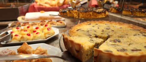 Variedad de productos horneados expuestos en un mostrador de vidrio, como tartas y pasteles.