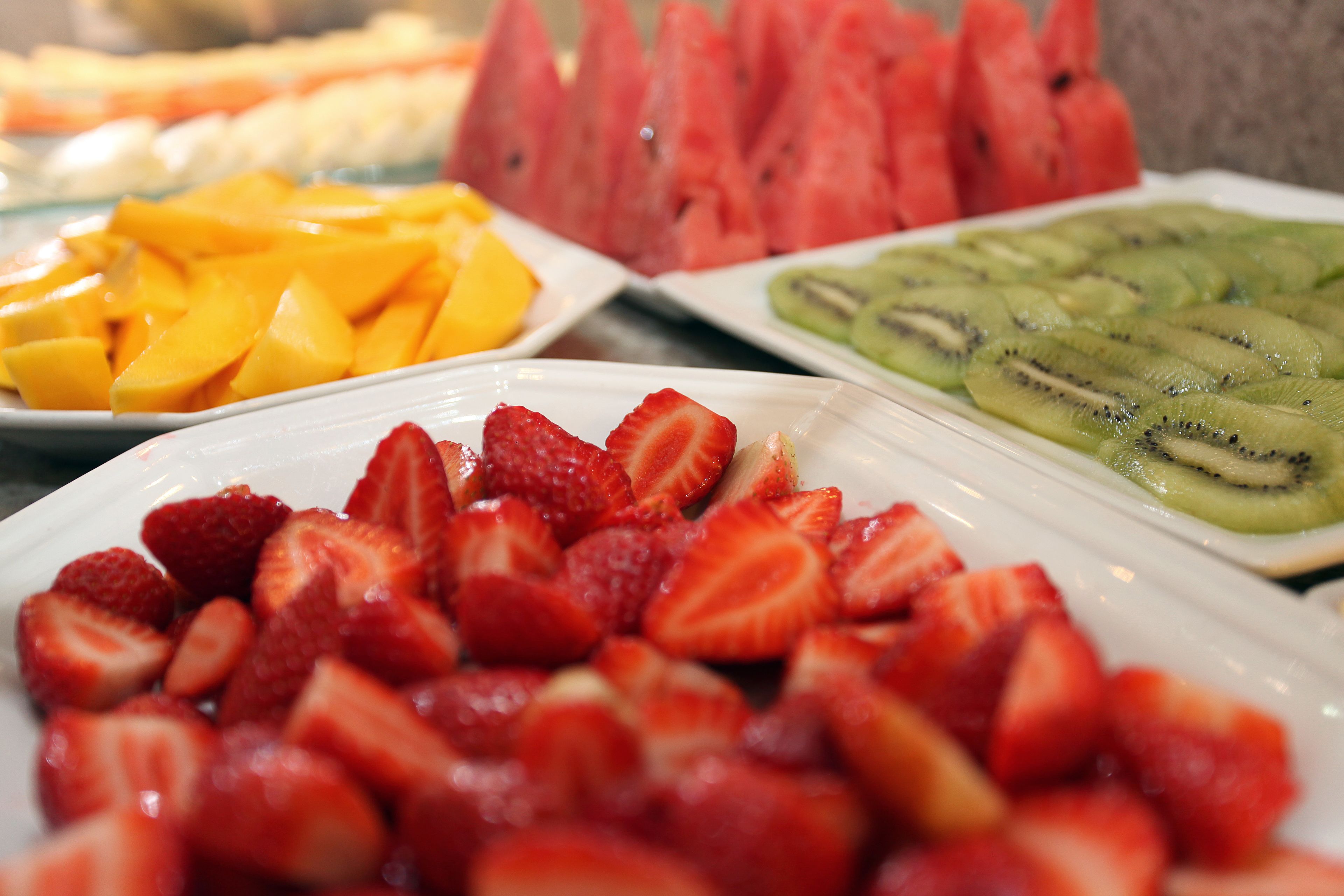 Variedad de frutas frescas como fresas, mangos, sandía y kiwi a la vista.
