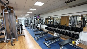 Un gimnasio con diversos equipos de ejercicio, como mancuernas y bancos.
