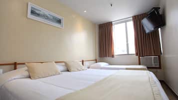 Habitación de hotel con dos camas, un televisor montado en la pared y una ventana con cortinas.