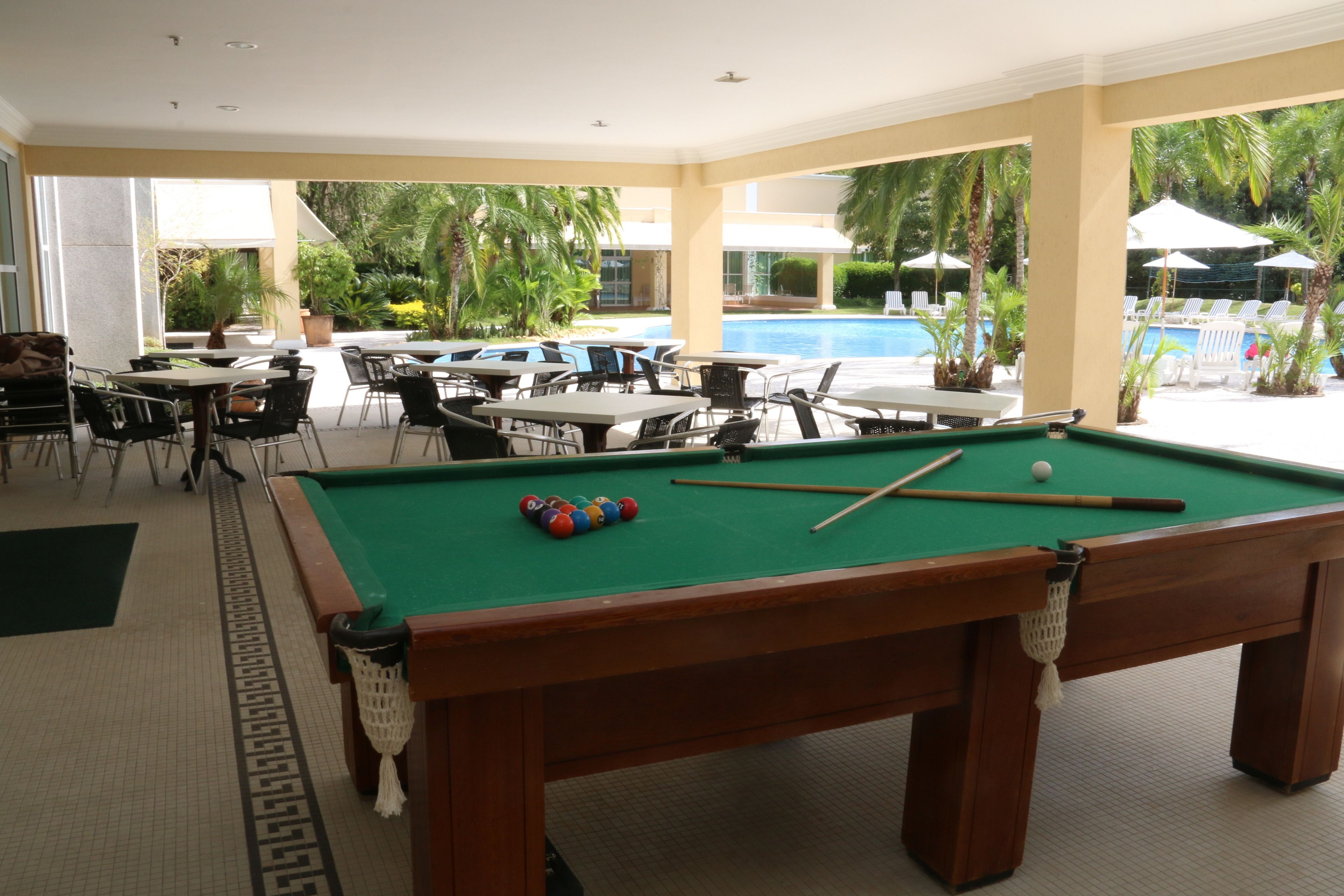 A pool table with balls, a pool table, and a pool table in a room with tables and chairs.