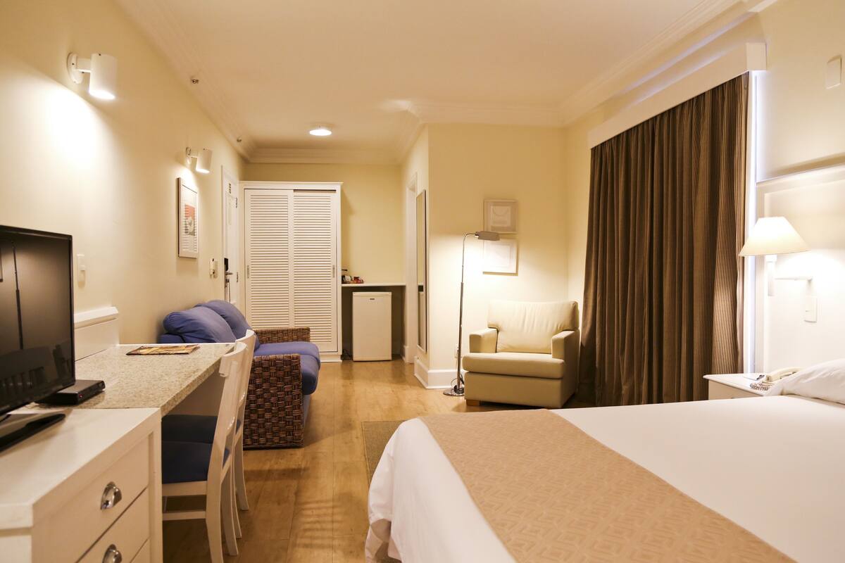 Een hotelkamer met een bed, bureau, stoel en een televisie.