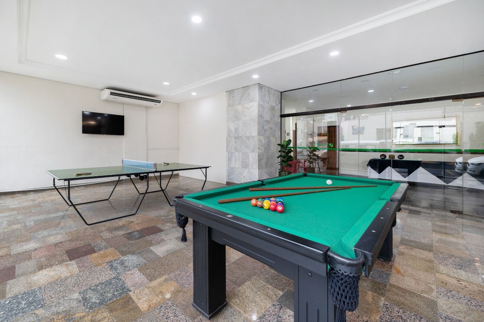 Une salle de billard équipée d’une table de billard, d’une table de ping-pong et d’un téléviseur fixé au mur.