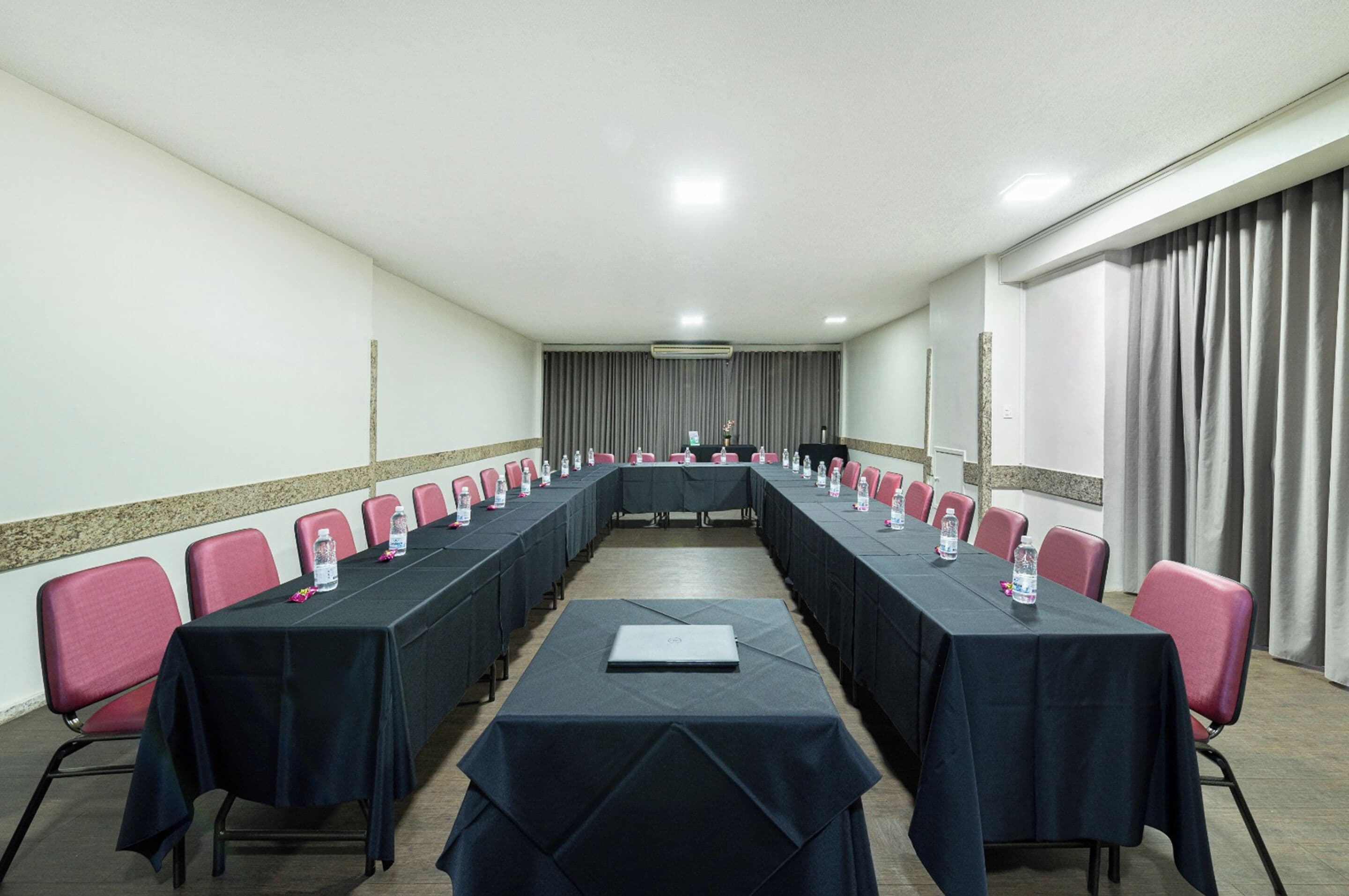 A conference room with a long table, red chairs, and water bottles.