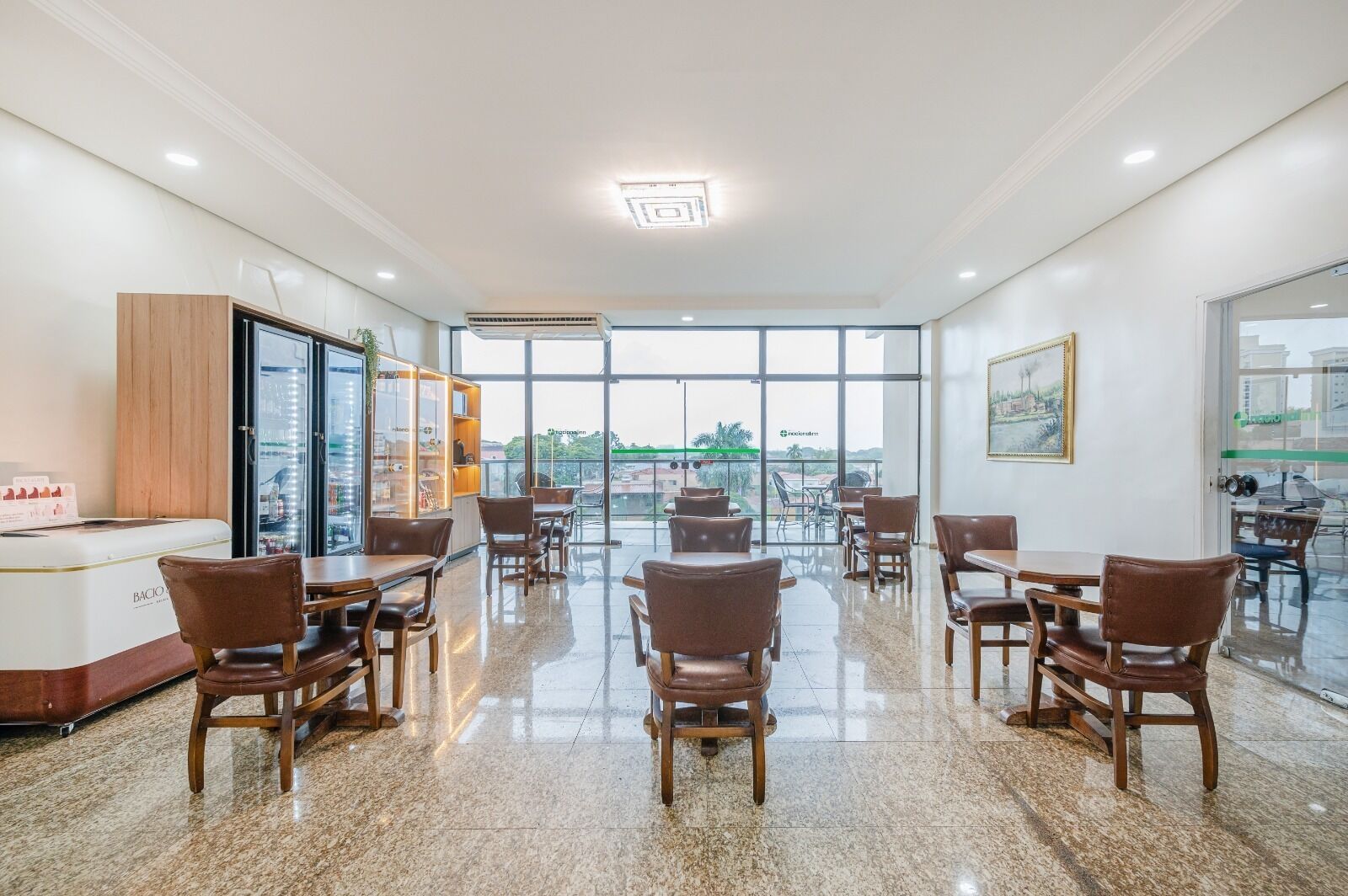 Uma ampla sala de jantar com pé direito alto e janelas grandes, com design moderno, móveis de madeira e um balcão central.
