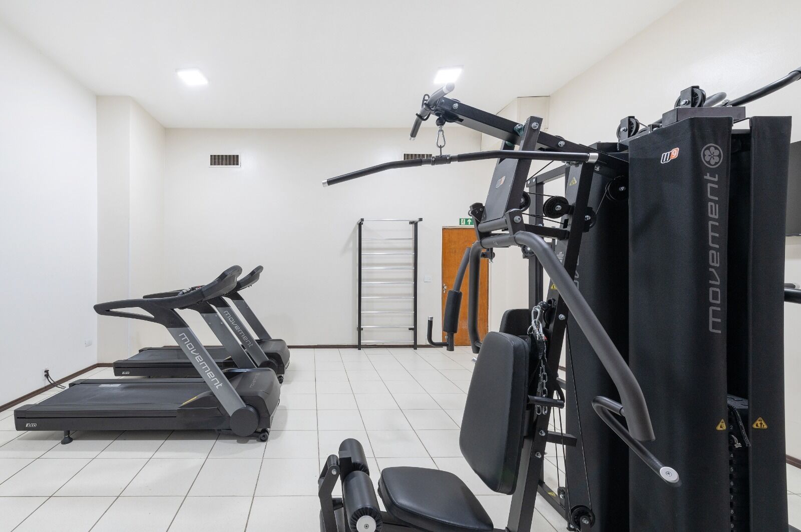 A gym with treadmills, weight machines, and a bench.