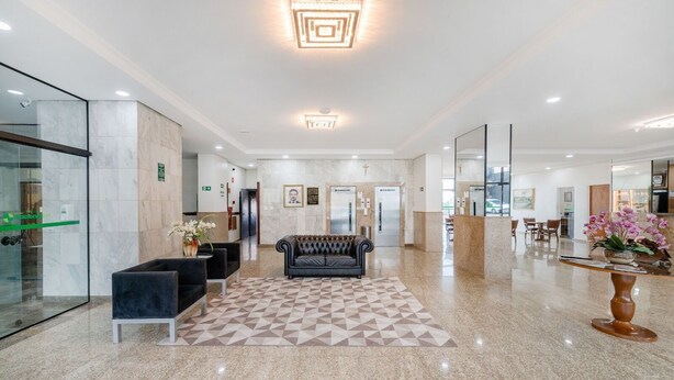 Un vestíbulo moderno con un rug geométrico, un sofá de cuero y una recepción.