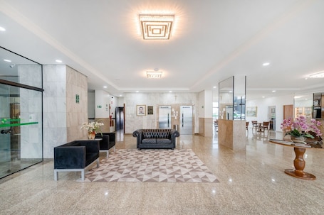 A modern lobby with a geometric patterned rug, a leather sofa, and a reception desk.