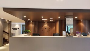 A modern reception desk with a clock, a plant, and a Sevenbox sign. - Hotel Nacional Distributed by Intercity (São José do Rio Preto)
