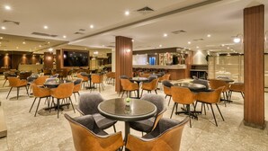 A modern restaurant with round tables and chairs, a bar area, and a large TV screen. - Hotel Nacional Distributed by Intercity (São José do Rio Preto)