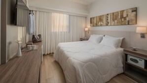 A modern hotel room with a large bed, a flat-screen TV, a bedside table with a lamp, and a painting on the wall. - Hotel Nacional Distributed by Intercity (São José do Rio Preto)