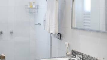 A modern bathroom with a white sink, a mirror, and a shower area.