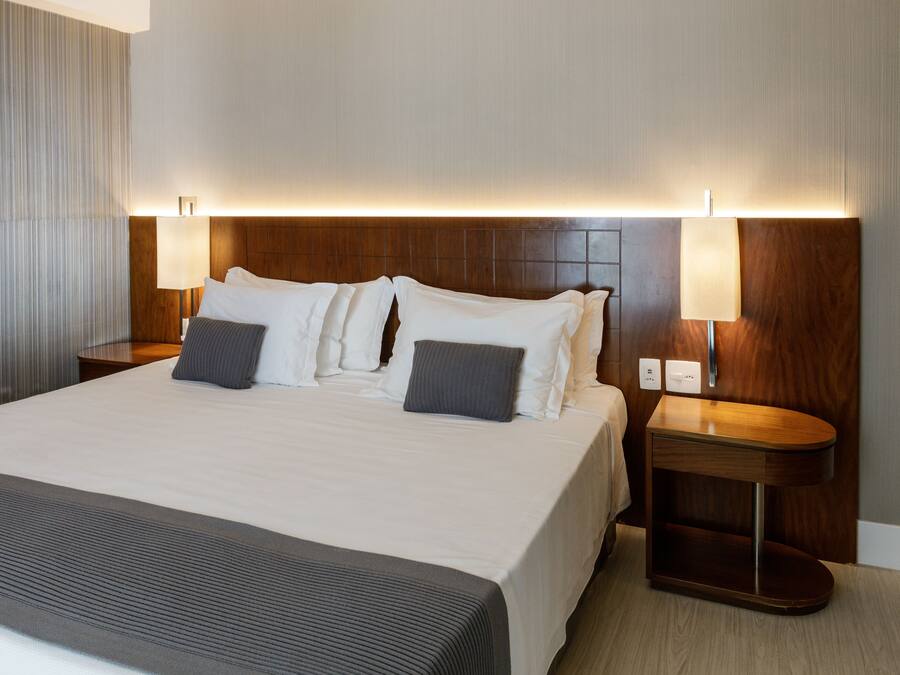 Ett hotellrum med en stor säng, två sängbord och en sänggavel med inbyggd belysning.