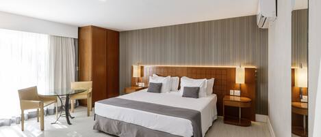 A modern hotel room with a large bed, bedside tables, a desk, and a chair.