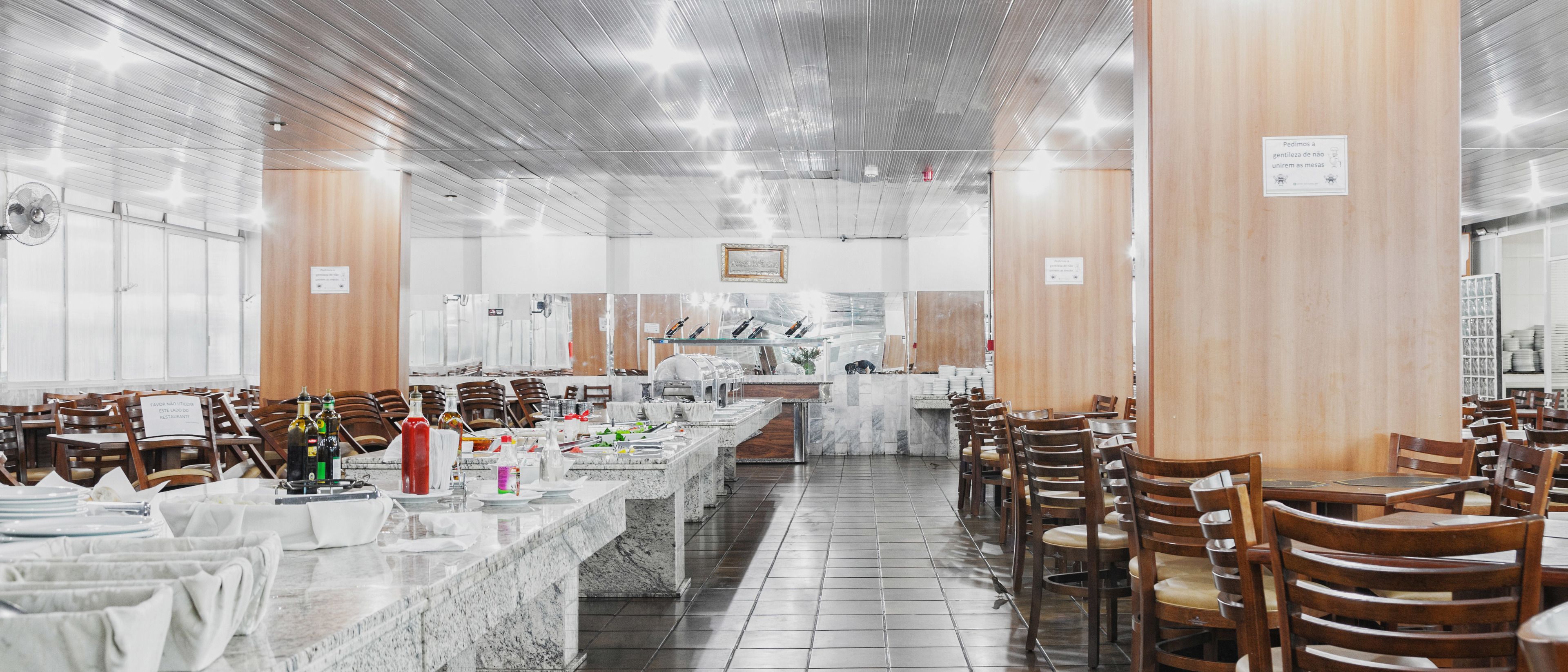 A restaurant with multiple dining tables and chairs, a marble counter, and a tiled floor.