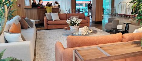 A modern lobby with a reception desk, sofas, and a coffee table.