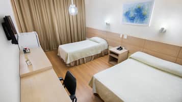 Ett hotellrum med två separata sängar, ett skrivbord med en stol, en tv och en tavla på väggen.