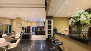Een hotel lobby met een receptiebalie, een bar, zitplaatsen en een zicht op de eetruimte.