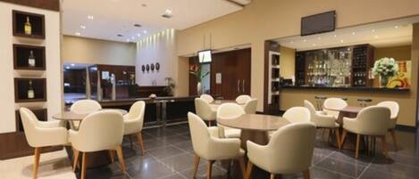 A modern hotel lobby with a bar area, multiple seating arrangements, and a reception desk.