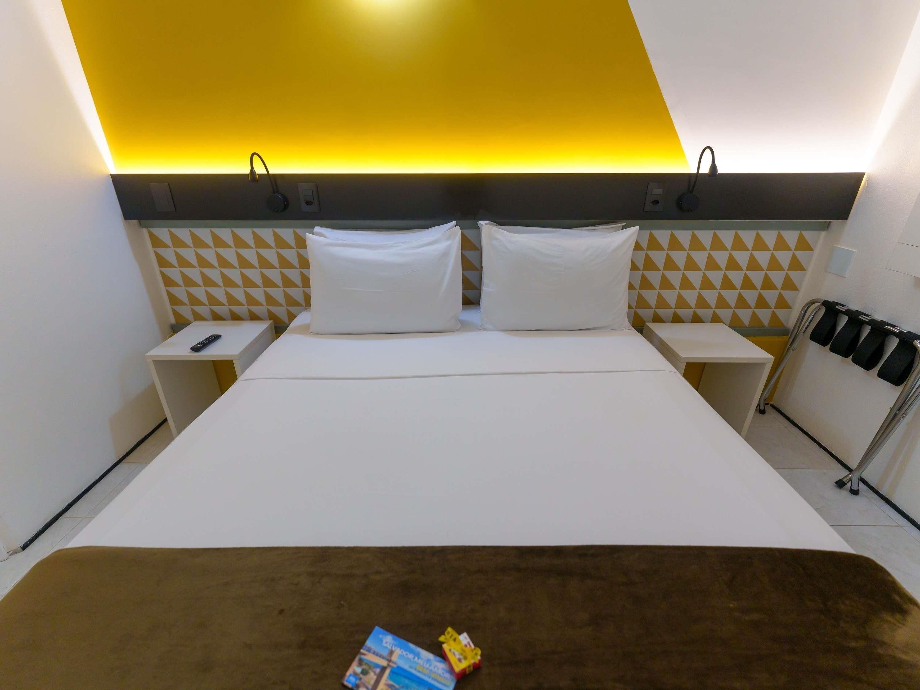 Een hotelkamer met een bed, twee nachtkastjes, een wandverwarming en een handdoekrek.