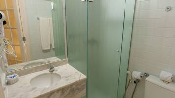 Ein Badezimmer mit Marmorwaschbecken, einer Glasdusche und einer Toilette.