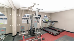 Ein Fitnessstudio mit Trainingsgeräten, Laufband und Spiegel.