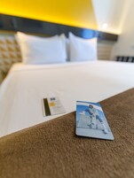 A neatly made bed with white linens and a brown headboard. A brochure is placed on the bed.