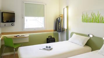 Een hotelkamer met een bed, een bureau, een stoel, een televisie en een raam.