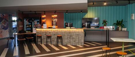 Un área de bar moderna con mostrador, taburetes y televisor.
