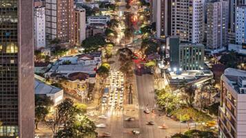 Paisagem urbana com uma avenida larga, edifícios altos e uma montanha ao fundo.