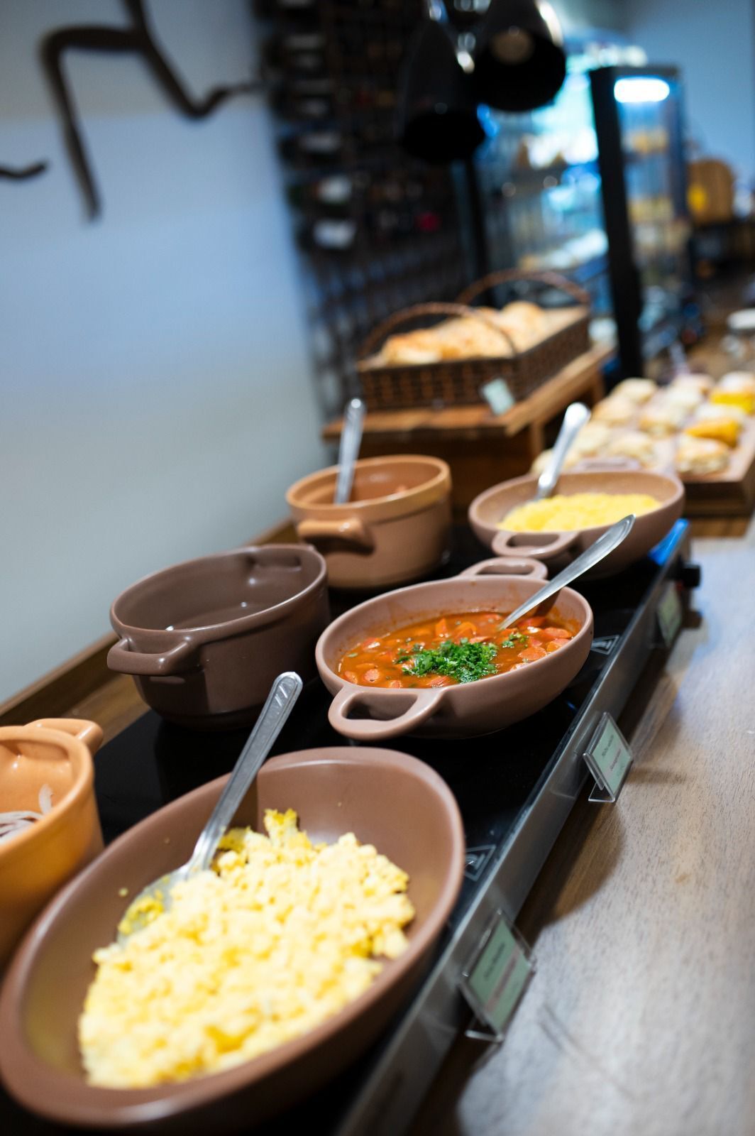 Een buffet met diverse gerechten, waaronder roerei, een tomatensoep en andere bereide maaltijden.