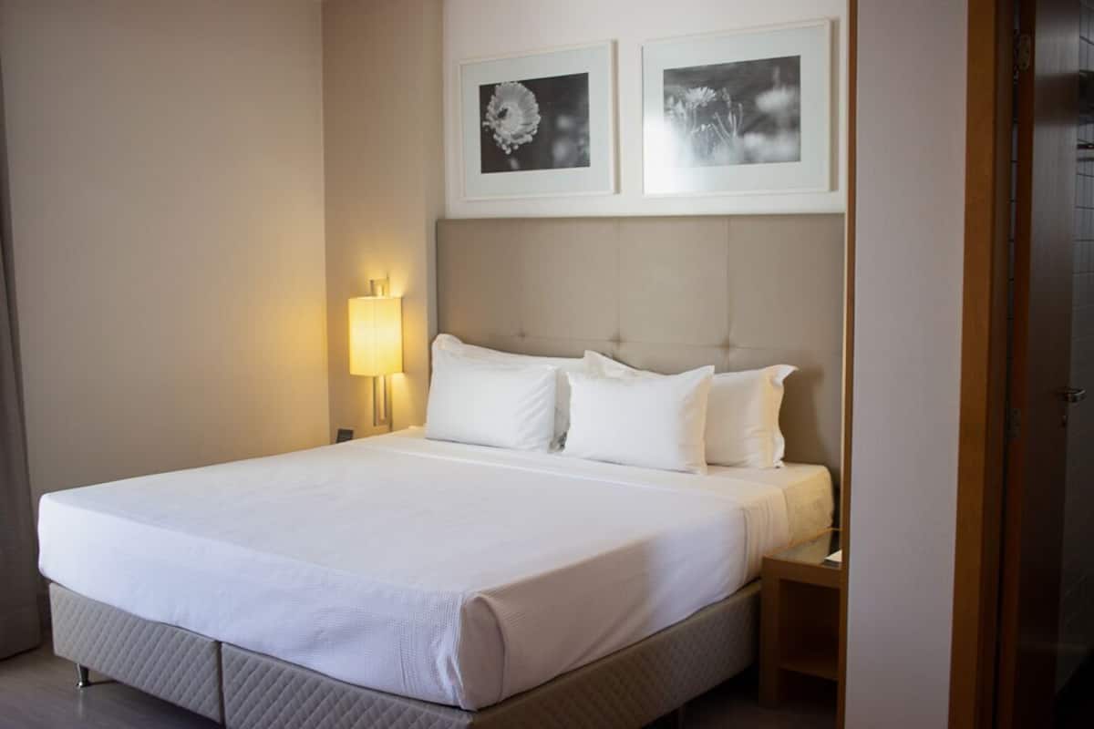 A hotel room with a bed, bedside tables, a lamp, and two framed pictures on the wall.