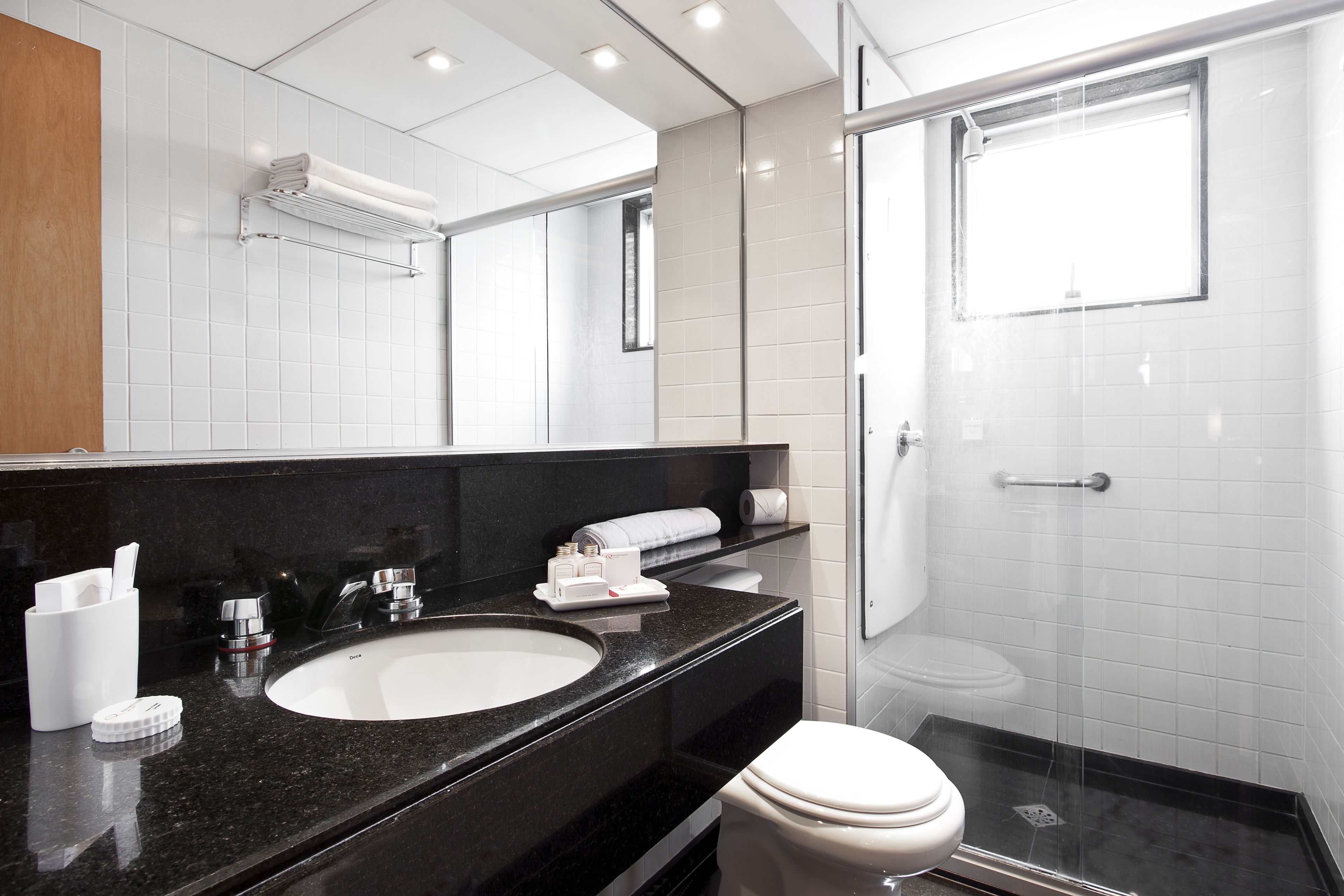 A modern bathroom with a black granite countertop, white sink, and a glass-enclosed shower.