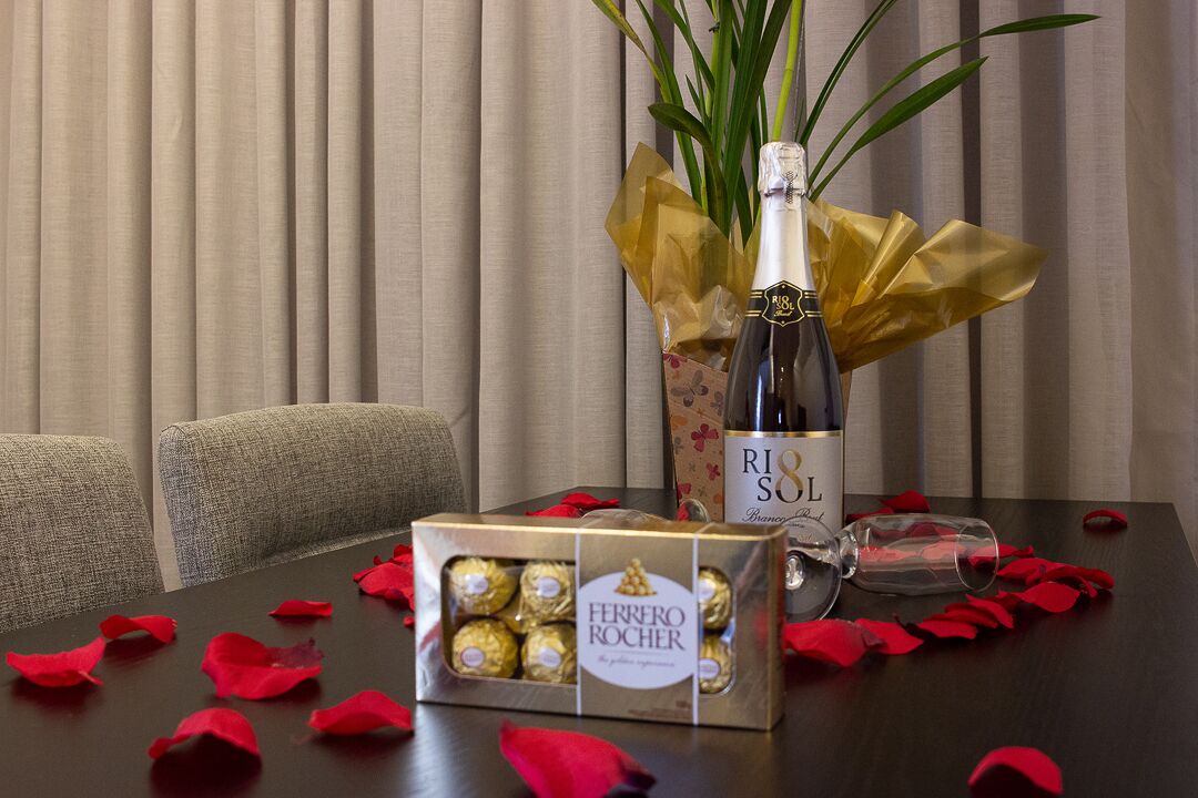 Una mesa con una botella de champán RIO SOL, una caja de bombones Ferrero Rocher y una copa.