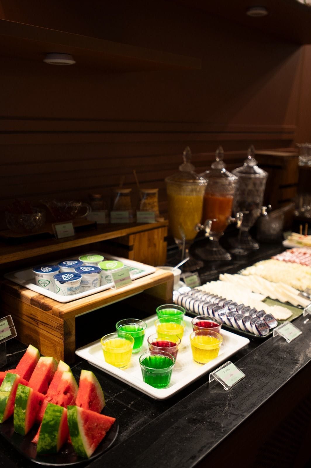 Un buffet proposant une variété de plats et de boissons, notamment des tranches de pastèque et des boissons colorées.