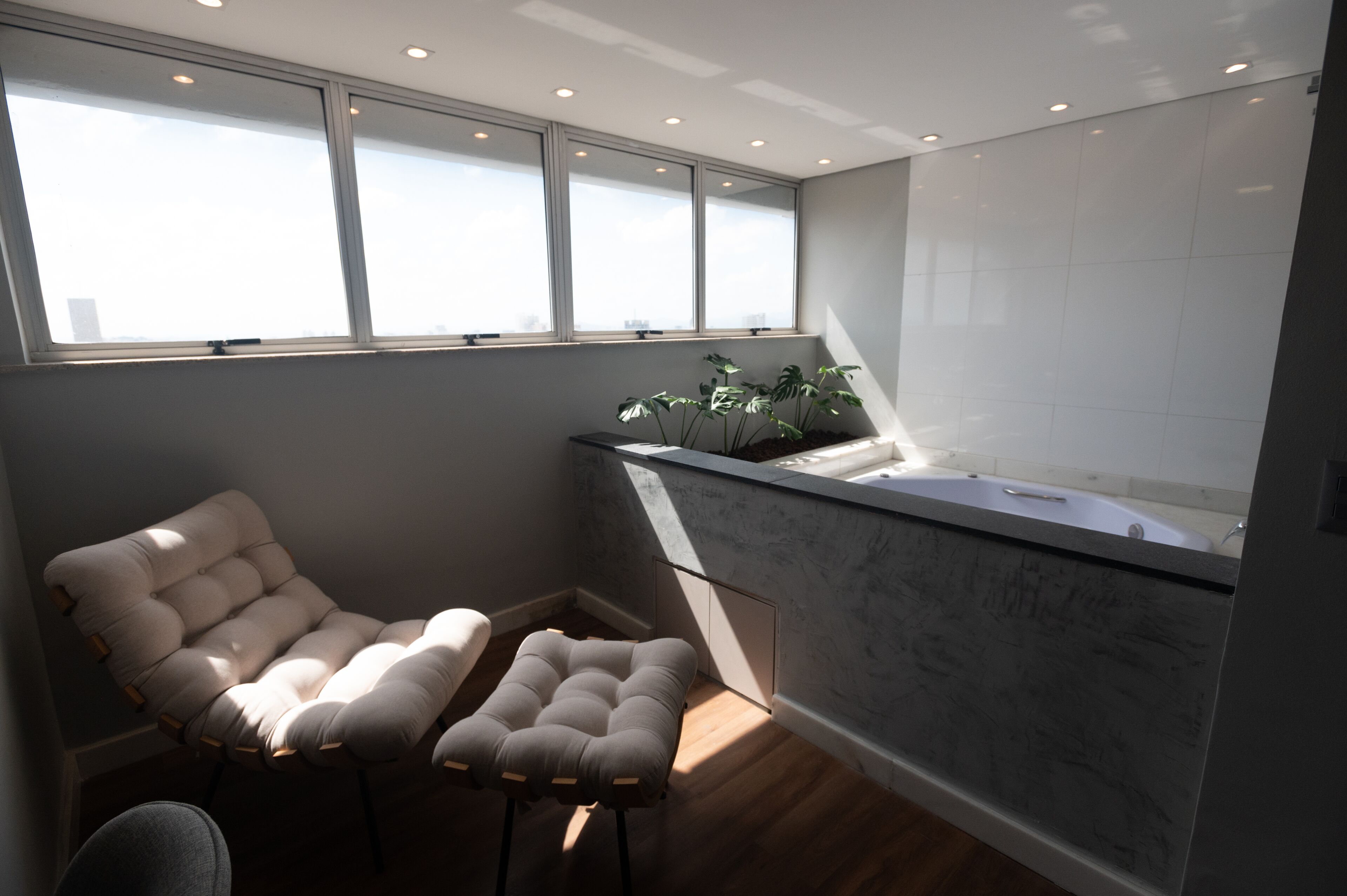 Uma casa de banho moderna com banheira, janela e uma planta.